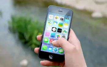 Ponsel dengan tampilan aplikasi pesan dan simbol keamanan di atas meja