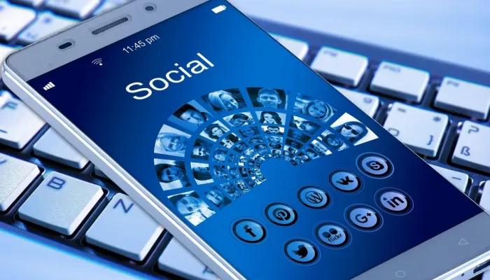 Ponsel dan laptop menampilkan aplikasi pesan saat pengguna memeriksa perangkat tertaut